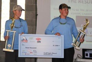 Two men holding a check in front of a screen.