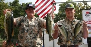 Two men in camouflage holding up their fish.