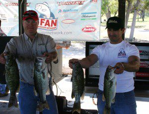 Two men holding up their fish at a tournament.