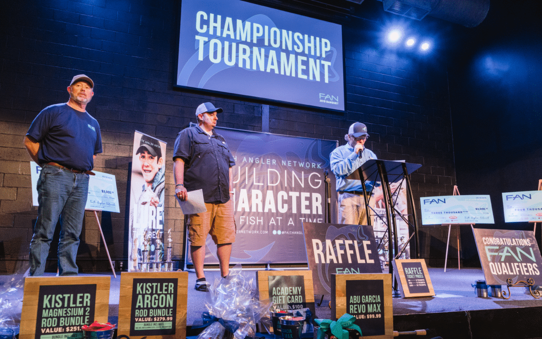 Three men standing on a stage with signs for the championship tournament.