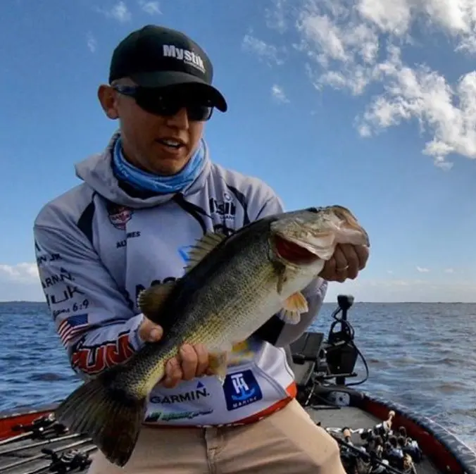 A man holding a large bass on a boat.