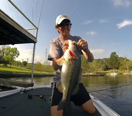 A man holding a large bass on a boat.