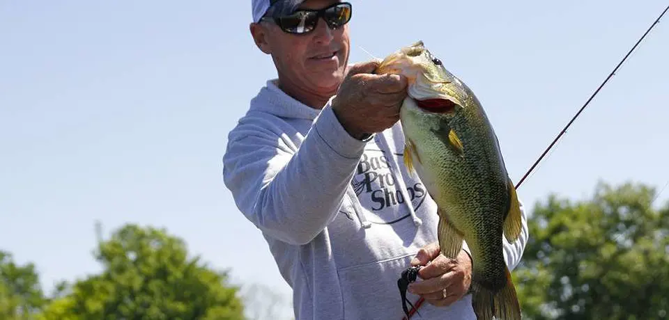 A man holding a large bass on a fly rod.