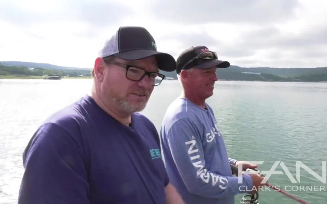 Two men standing on a boat next to a body of water.