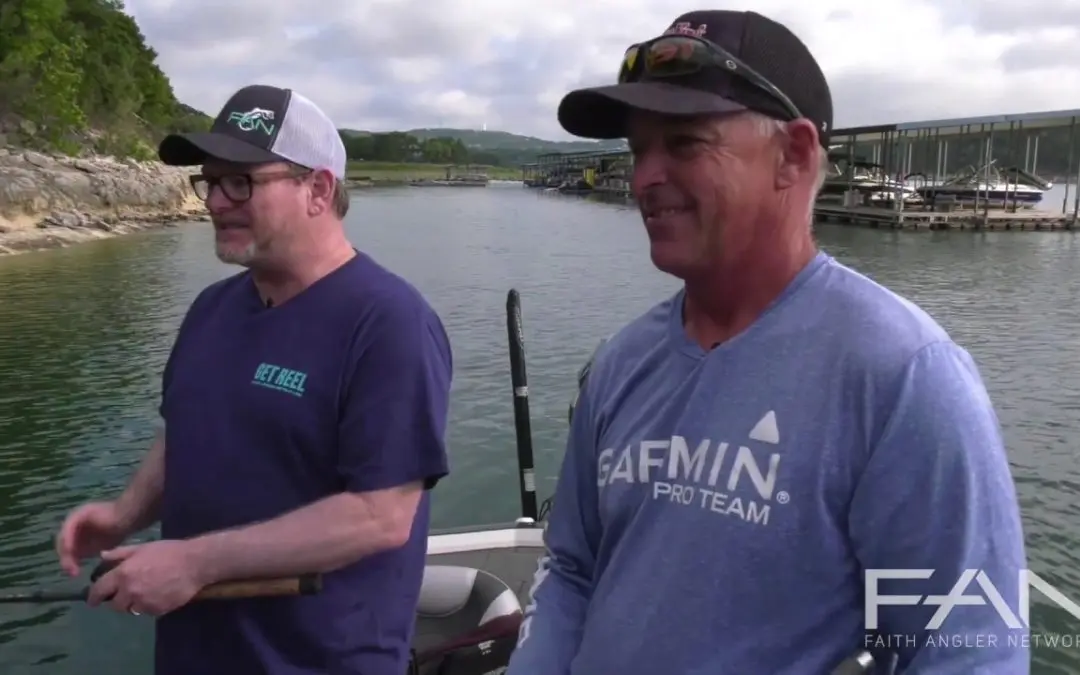 Two men on a boat talking about fishing.