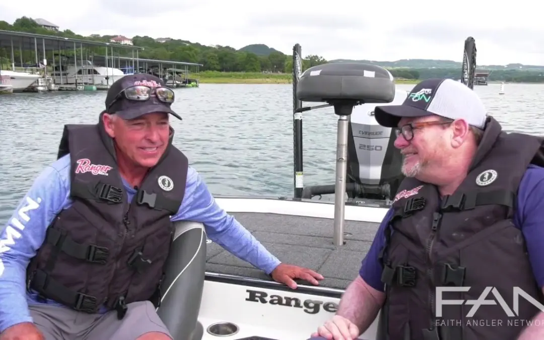 Two men in life jackets talking on a boat.
