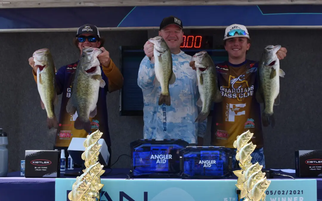 Three men holding up fish on a table.