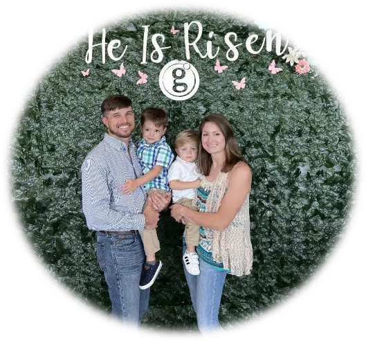A family is posing for the camera in front of a hedge.