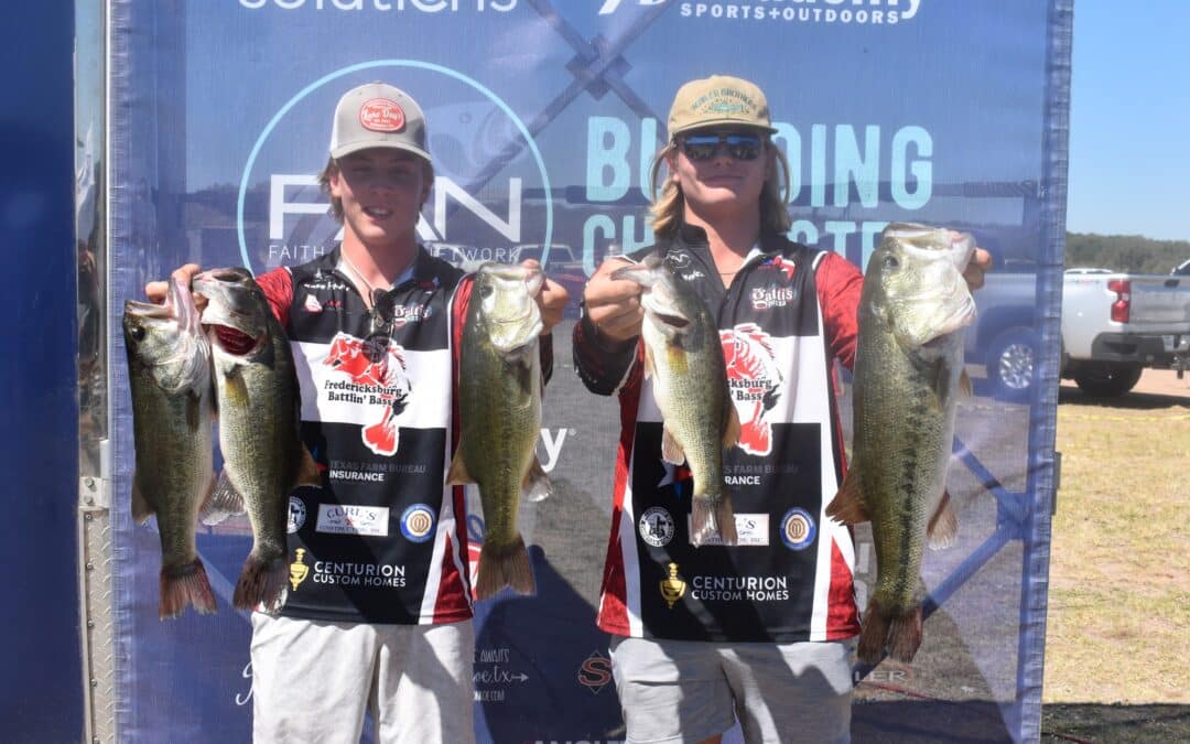 Two men holding up their fish at a tournament.