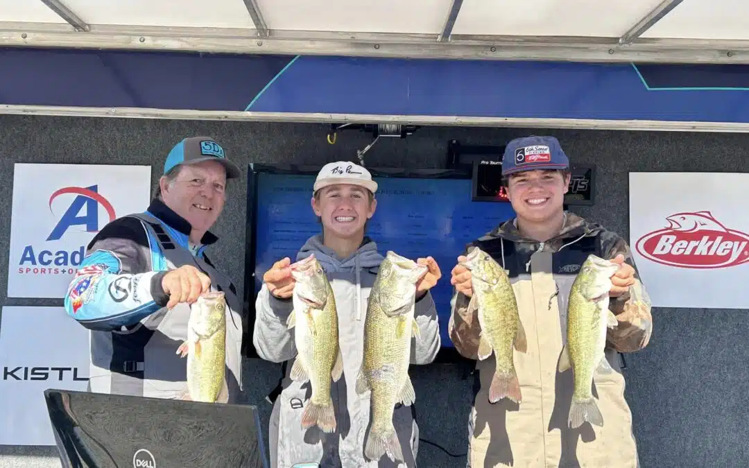Three men holding up fish in front of a blue wall.