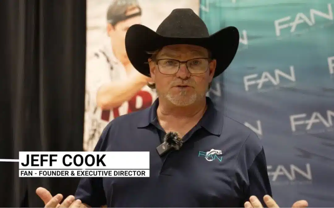Man speaking at an event in cowboy hat.